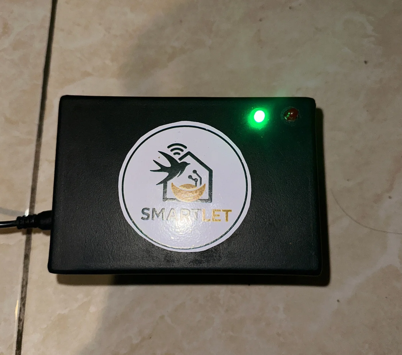 Assembled Smartlet device enclosure with a green status indicator, mounted on a wall
